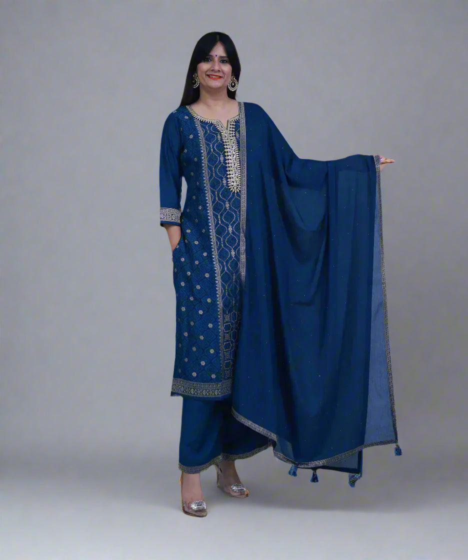 Woman wearing a blue traditional outfit with a matching dupatta against a gray background